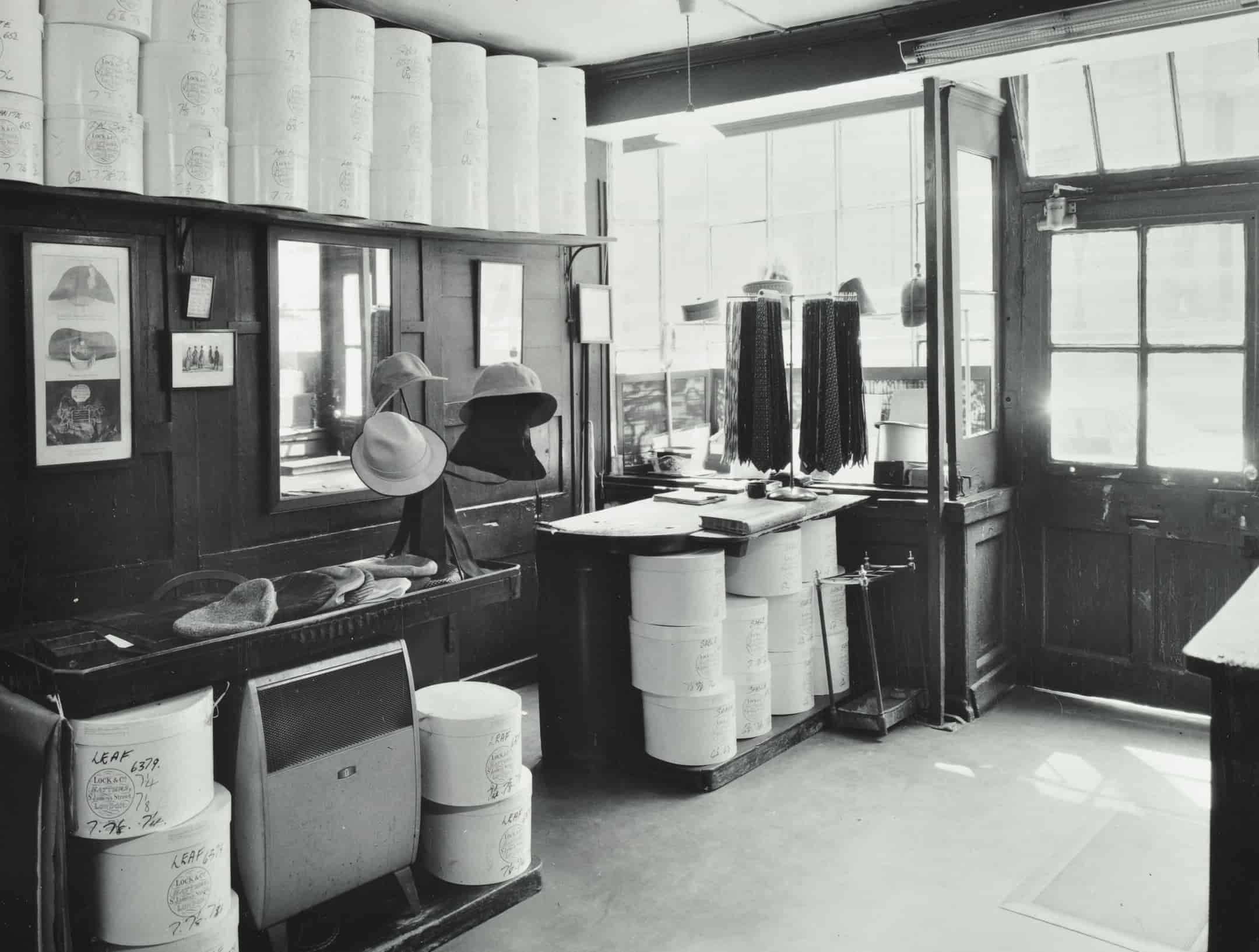 Interior of shop, hats on stands, hat making stations. 