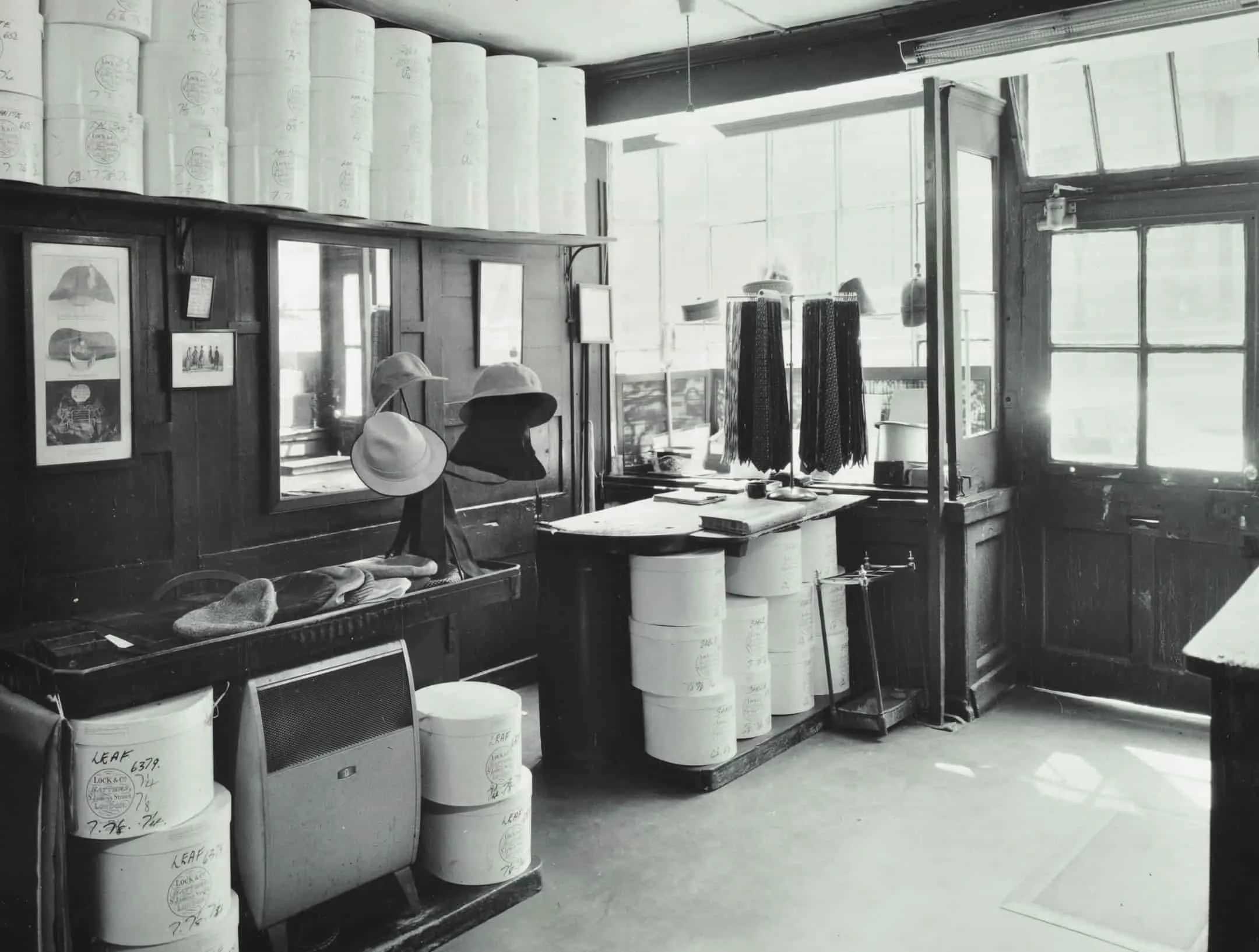Interior of shop, hats on stands, hat making stations.