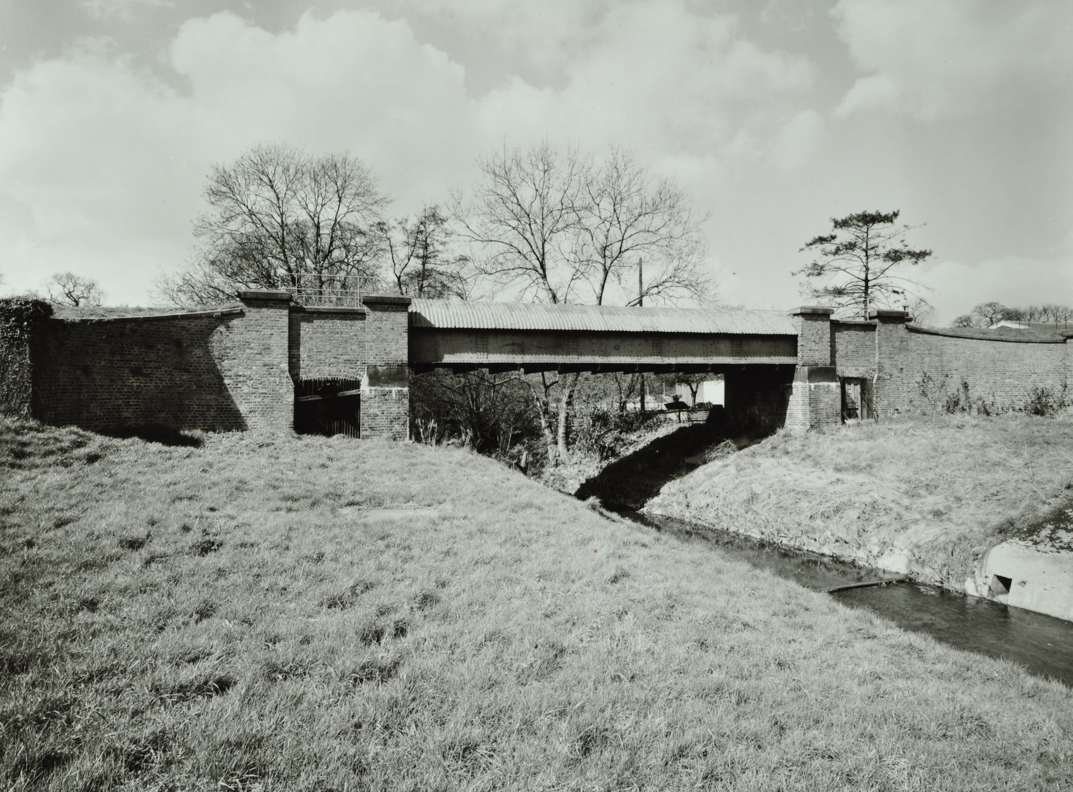 a bridge over a river with a grassy bank in the foreground