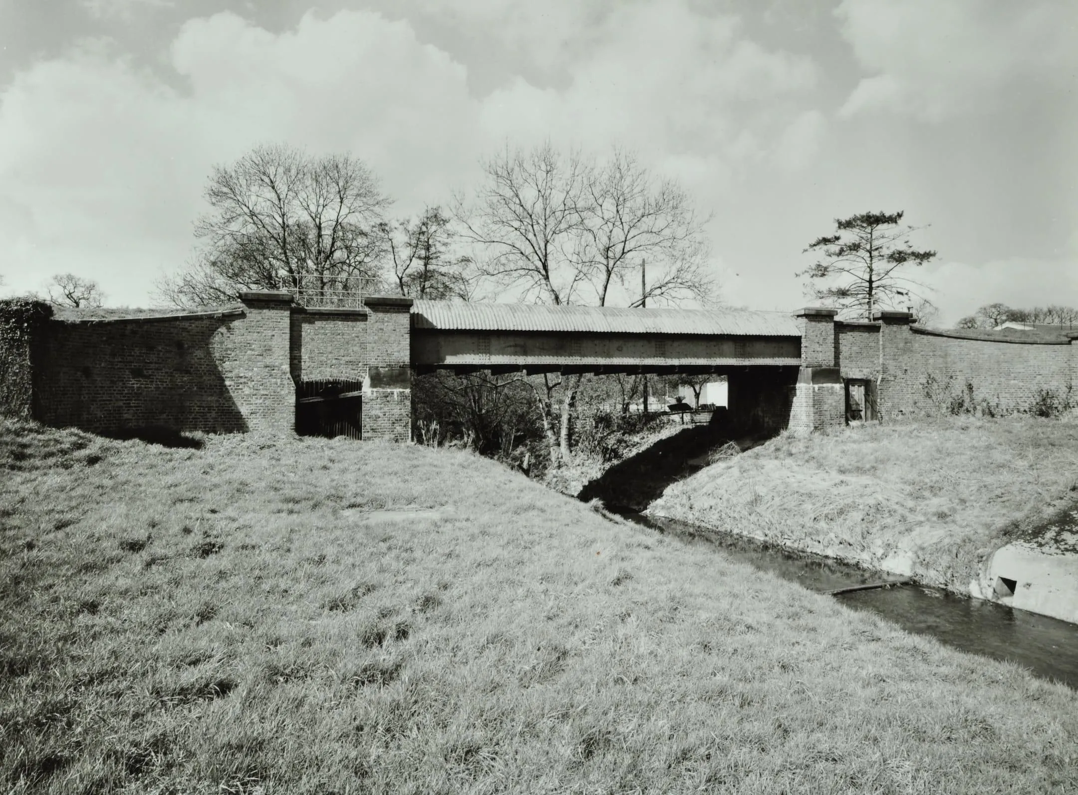 a bridge over a river with a grassy bank in the foreground
