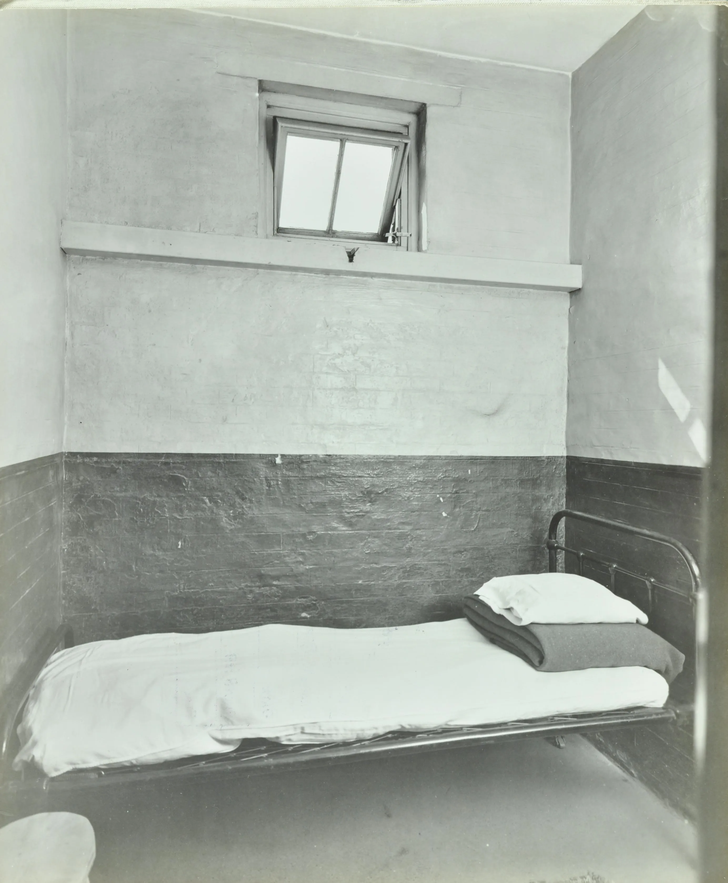 Iron bed in a cubicle at Wandsworth workhouse with a small window open