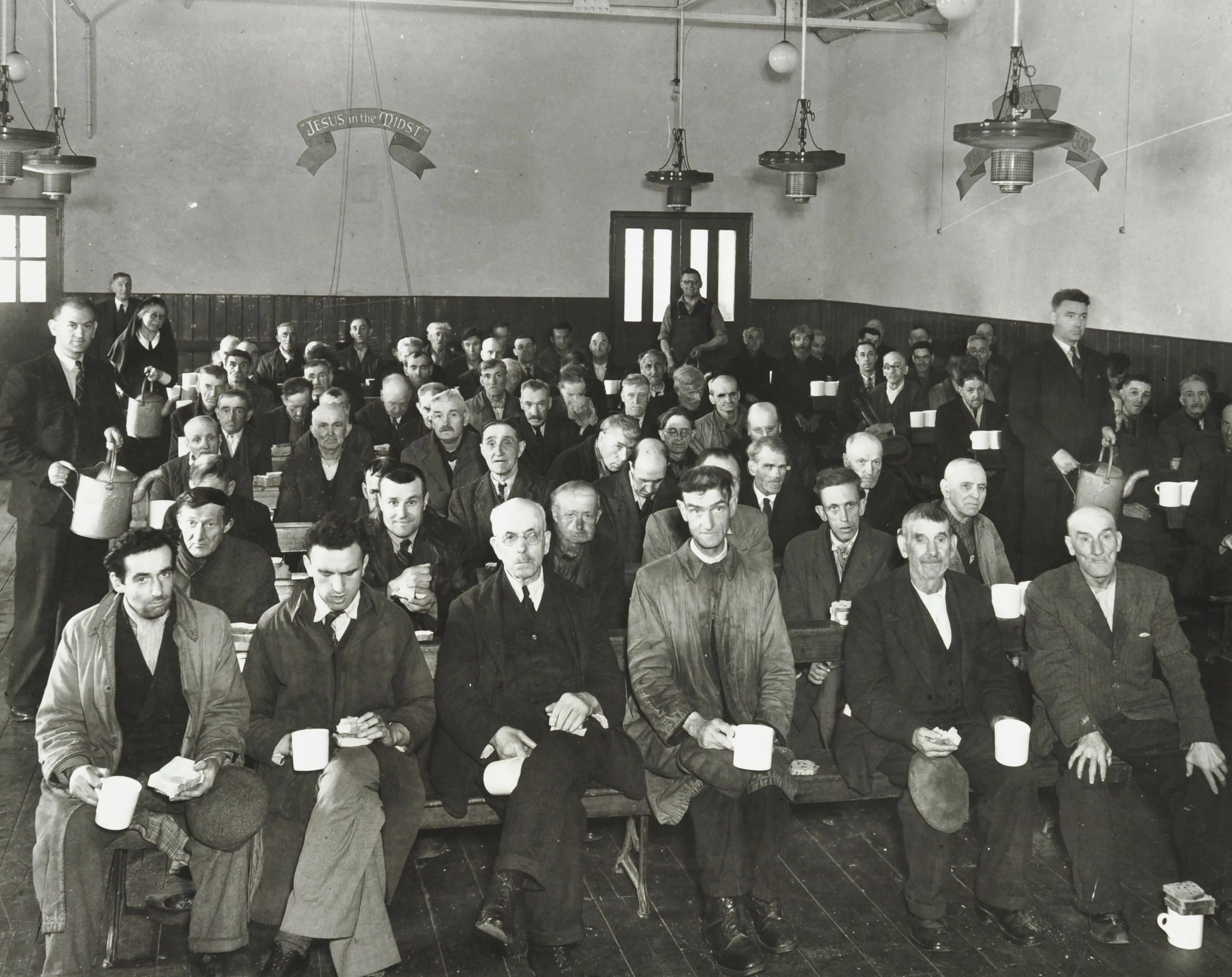 Men in a church hall with tea and bread