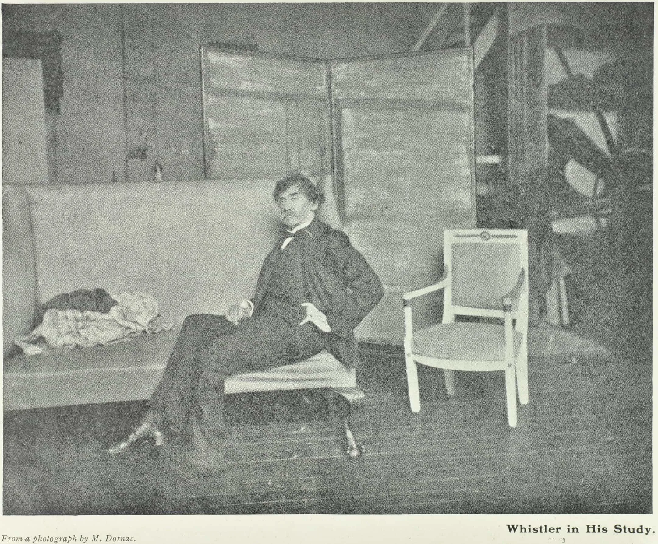 a man sits at an angle on a sofa with a screen behind him