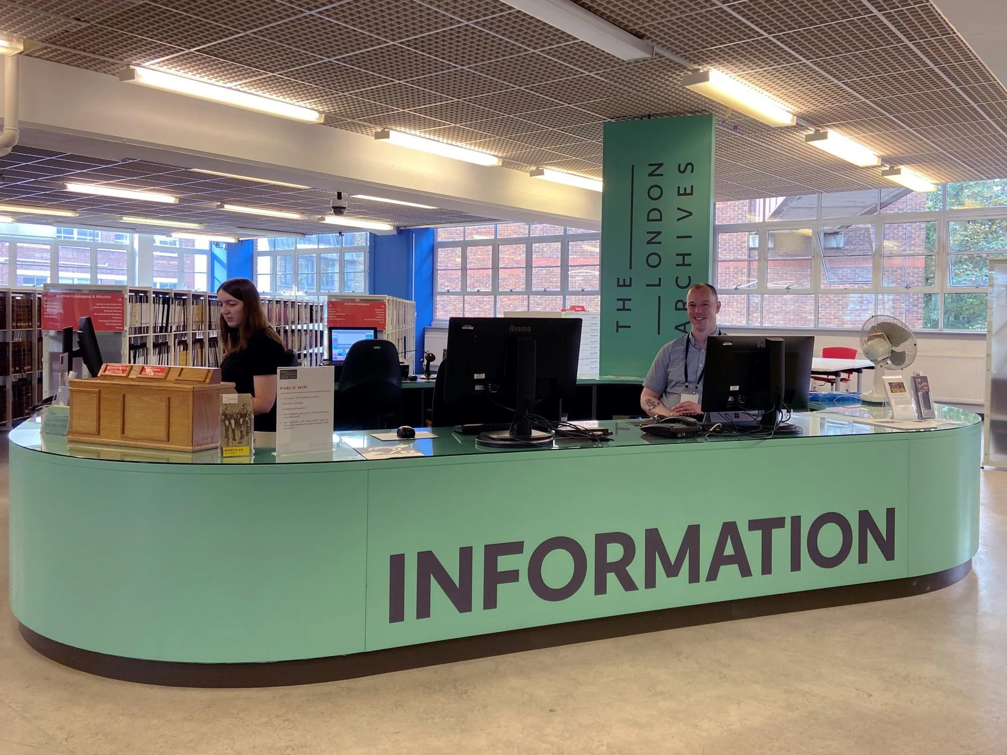 Two people seated at the Information Desk at The London Archives