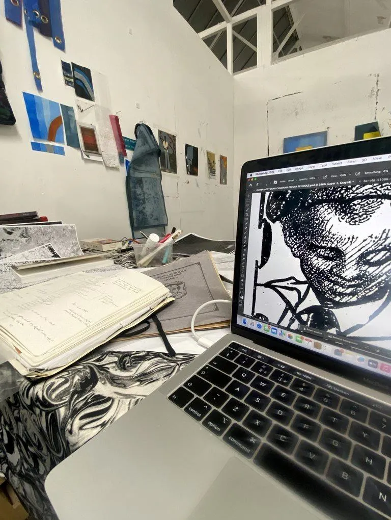 A laptop on a crowded desk in an artists studio