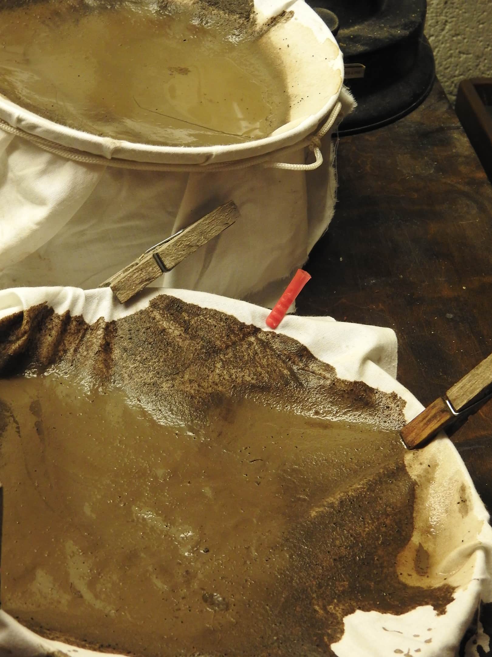 Canvas stretched and pegged to a basket while being stained with soil