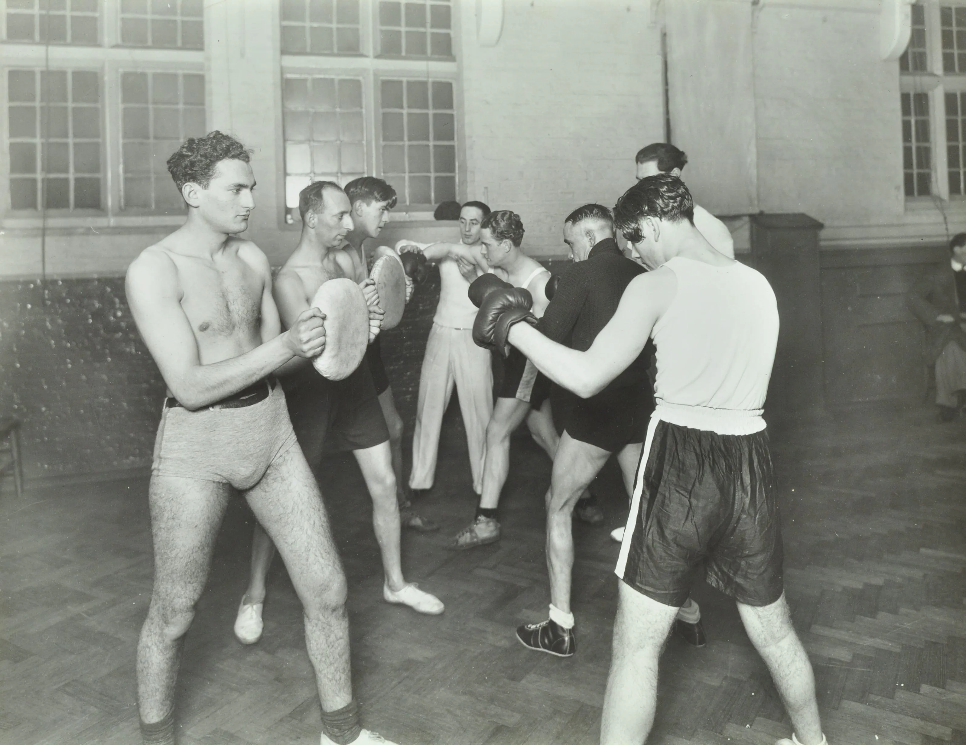 Men in shorts with boxing gloves and practise pads
