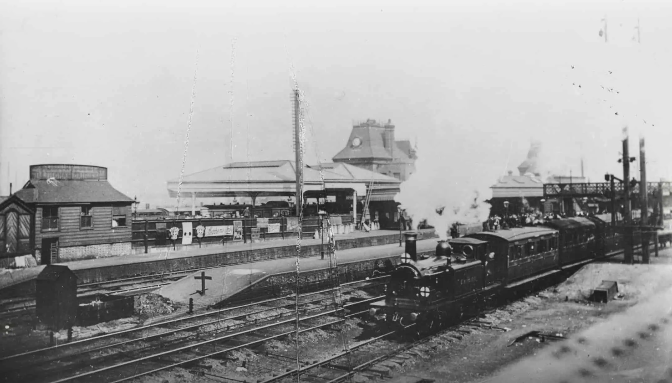 Steam train on the railway, train platform behind the train with a few people in the background