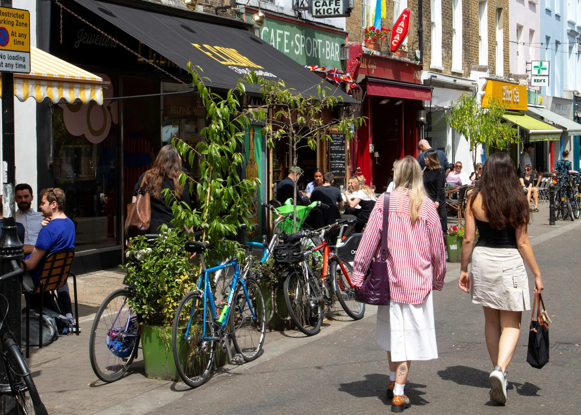 People walking down the road with cafes and shops on both sides of the street
