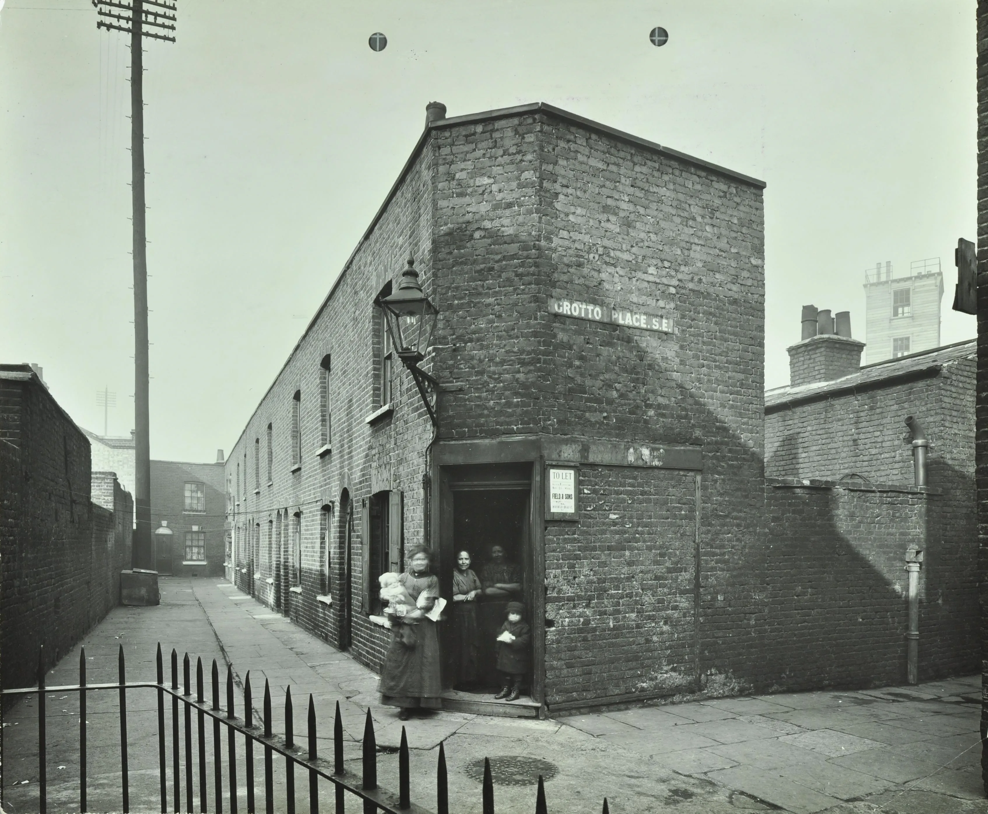 Nineteenth-century terrace houses with a group of women and children outside an open door