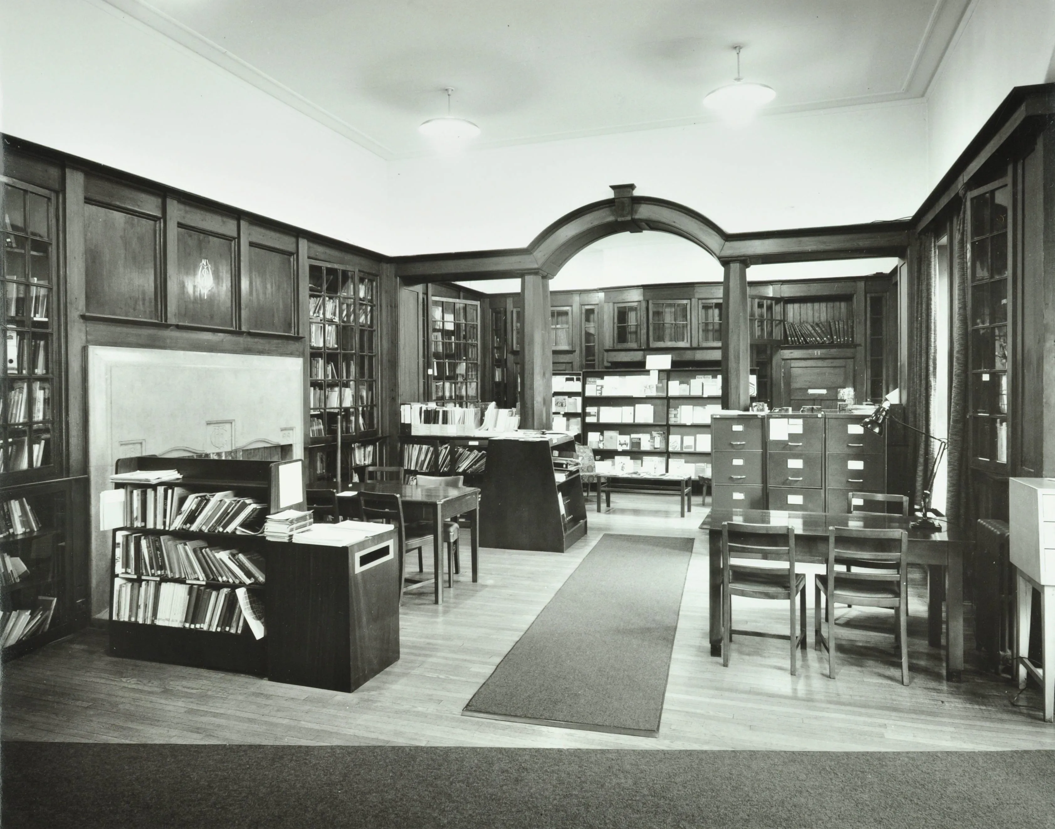 interior of a library with books on shelves and a recess at the back of the room with more books