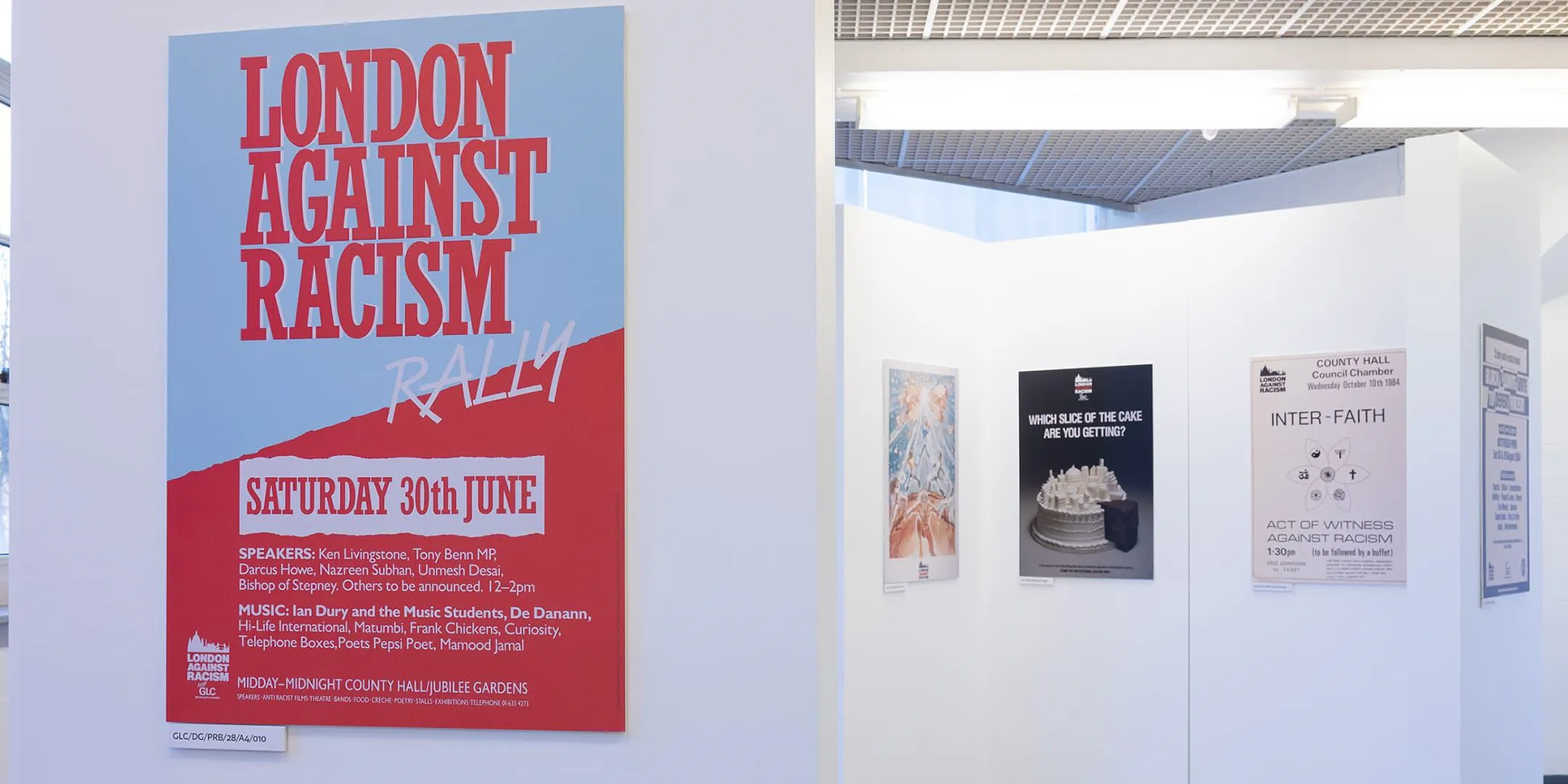 Exhibition of posters on walls, including one advertising an anti-racism rally