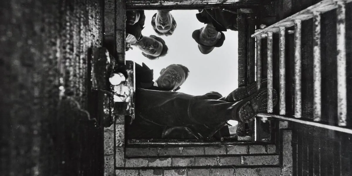 men-looking-down-sewer