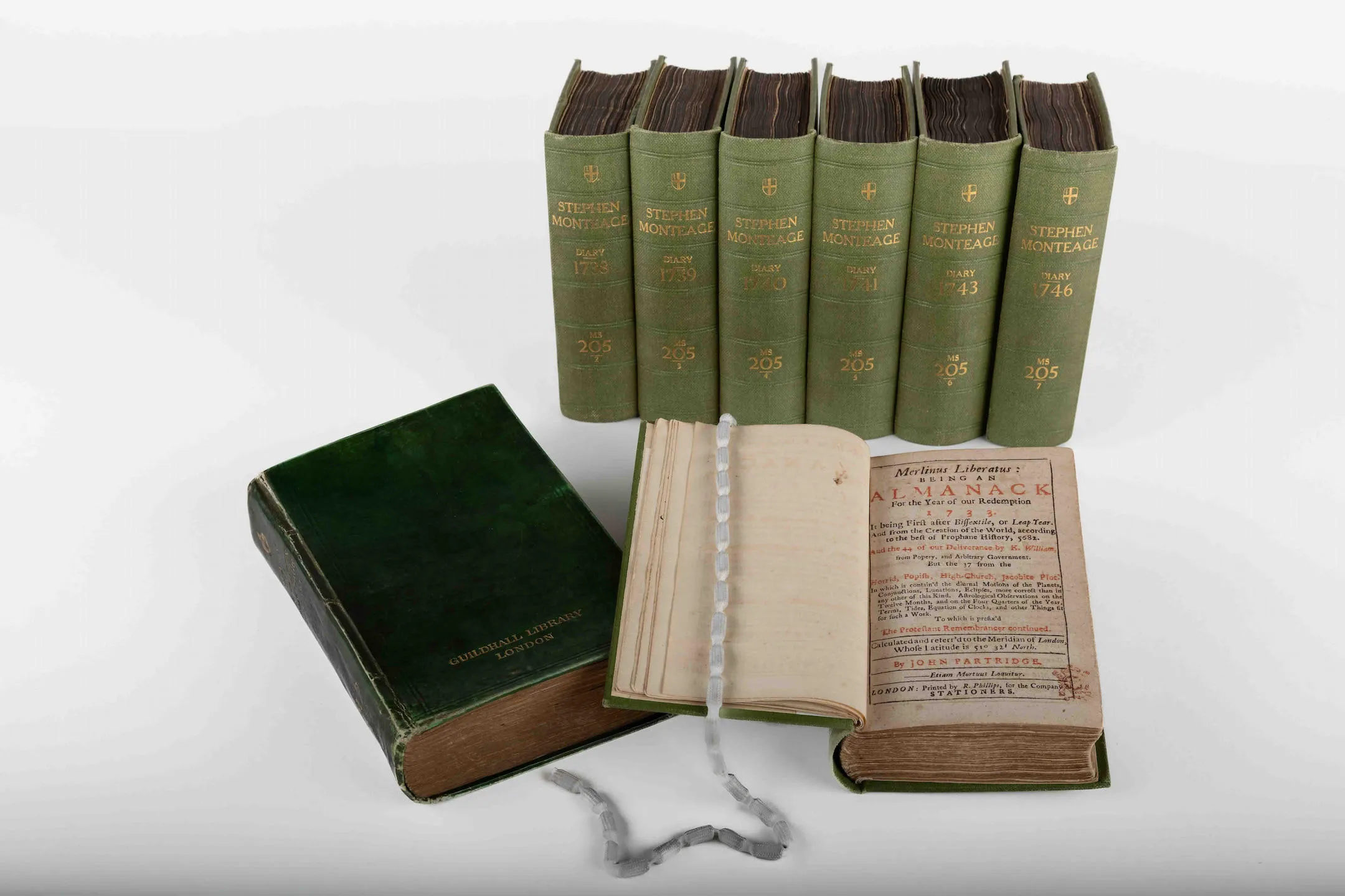 green diaries lined up with one book on an open page