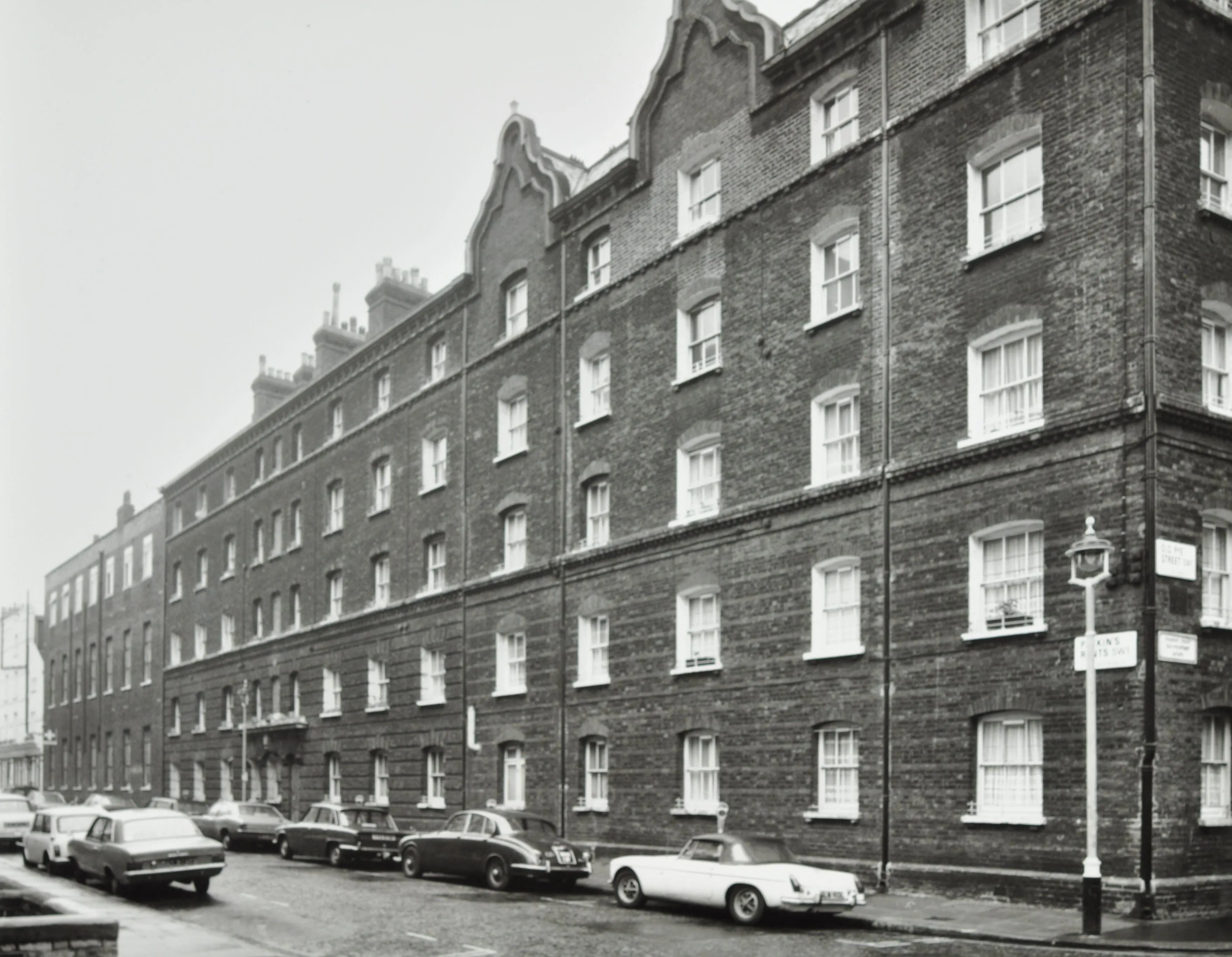 five storey housing block with cars parked outside