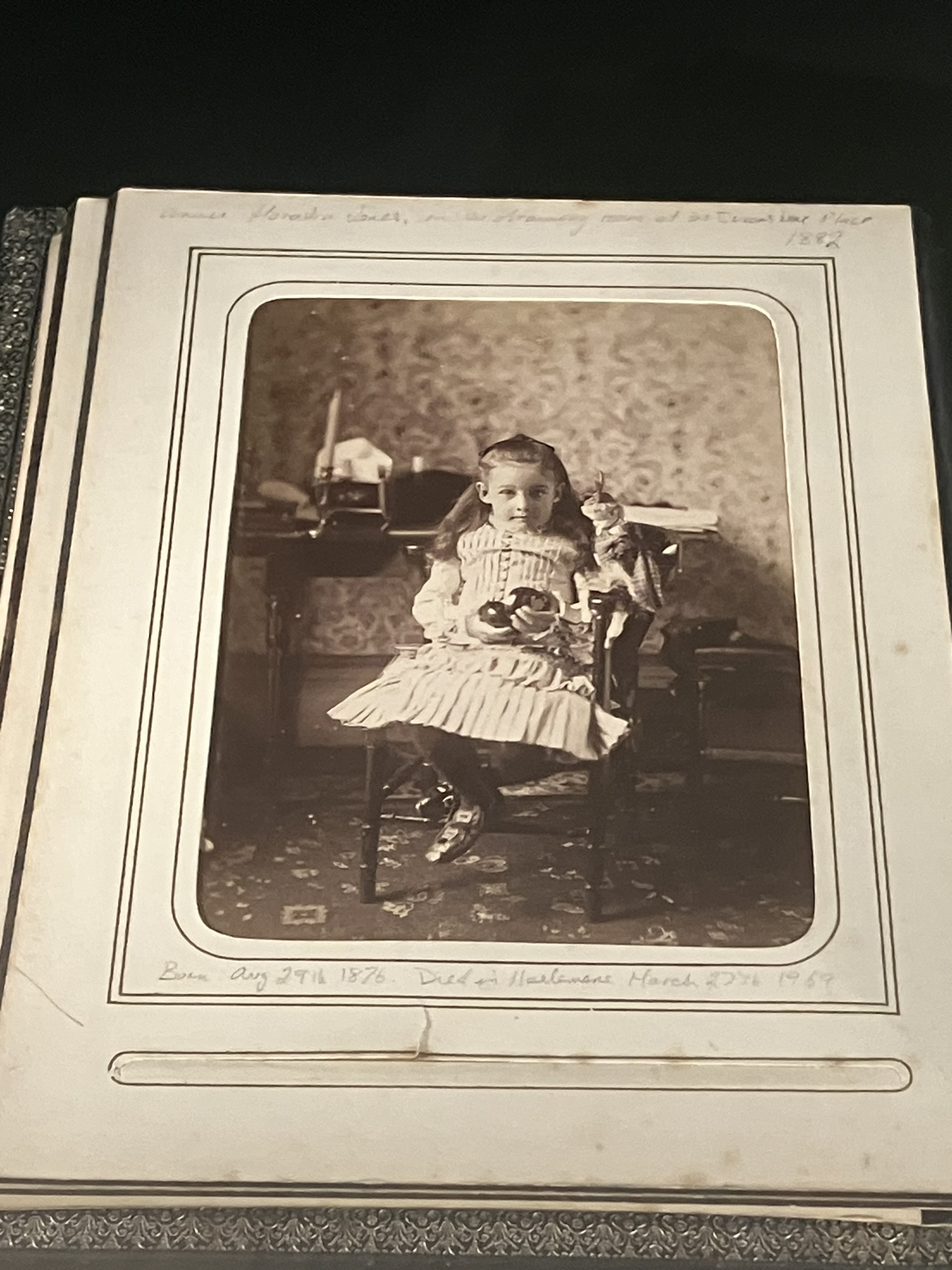 Photo album showing a young girl in a chair in a Victorian interior.
