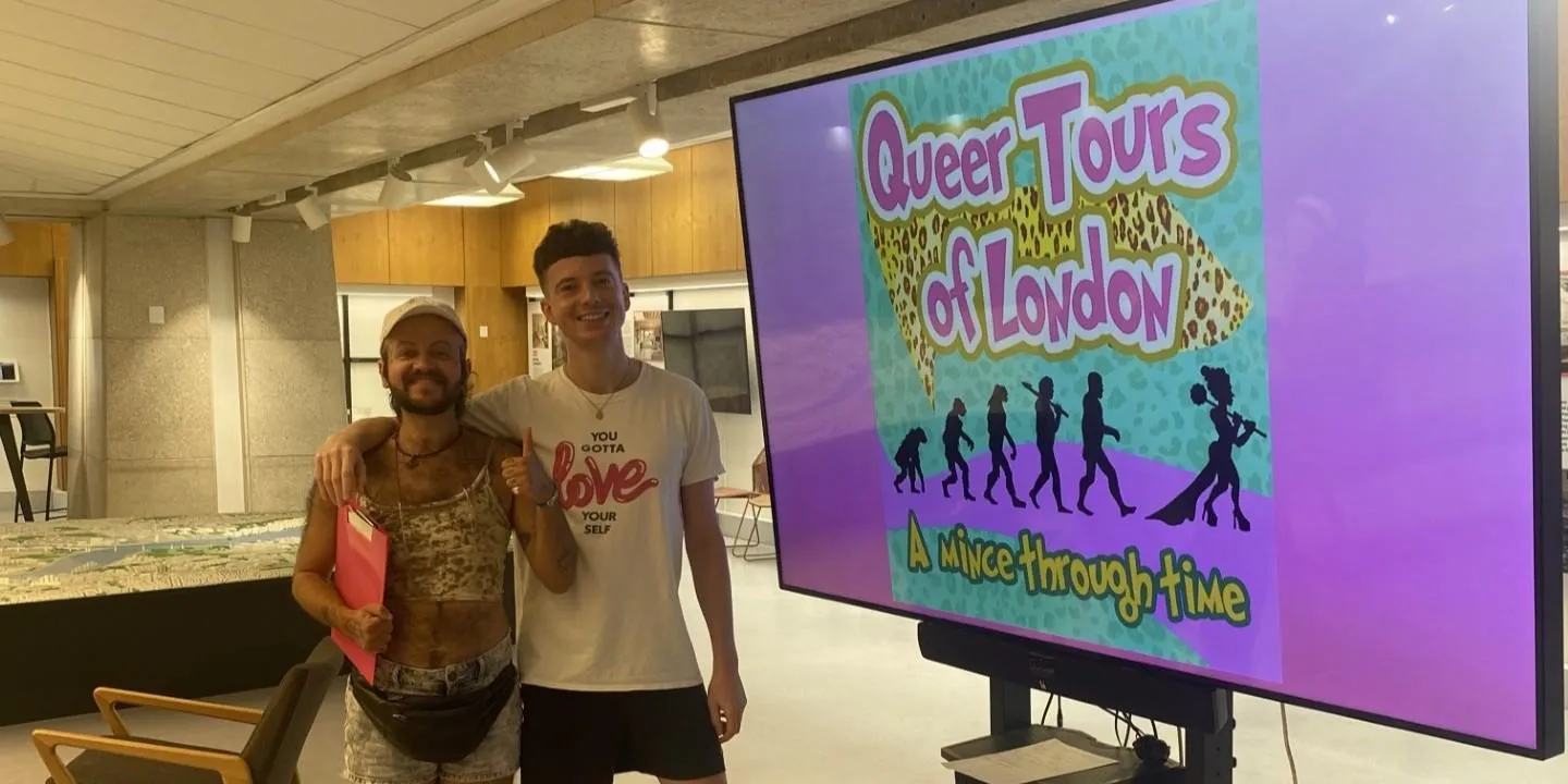 Two men standing to the side of a colourful screen with "Queer Tours of London" in purple font