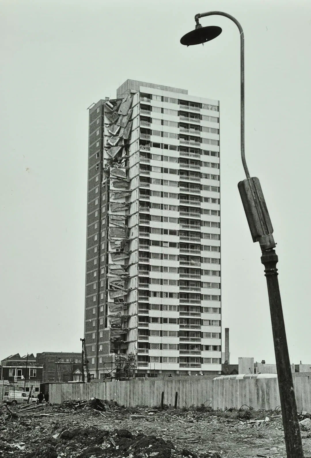 Tower block damaged from explosion with a crooked lamp post in the foreground