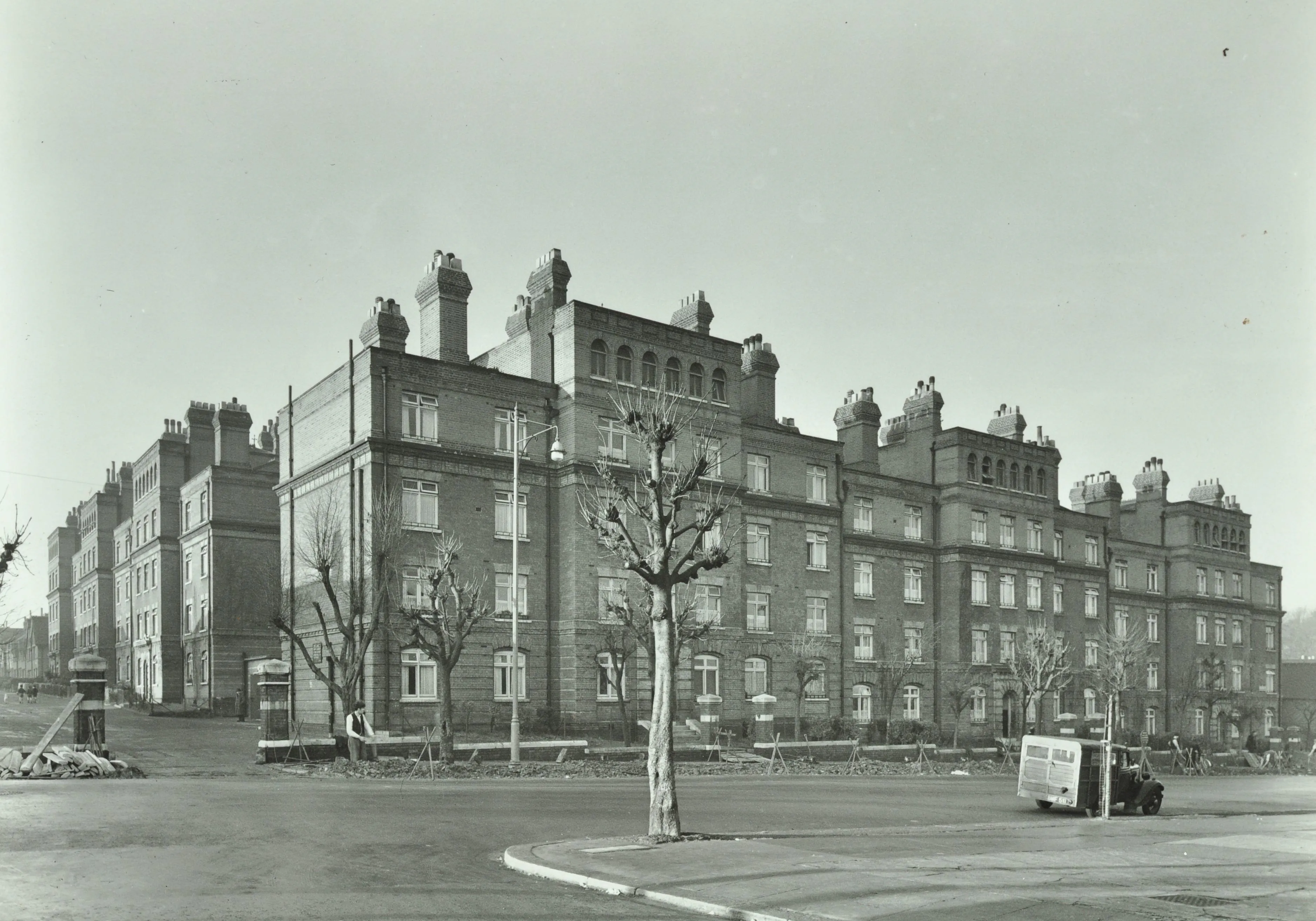 five storey housing estate buildings with trees and a van in the foreground