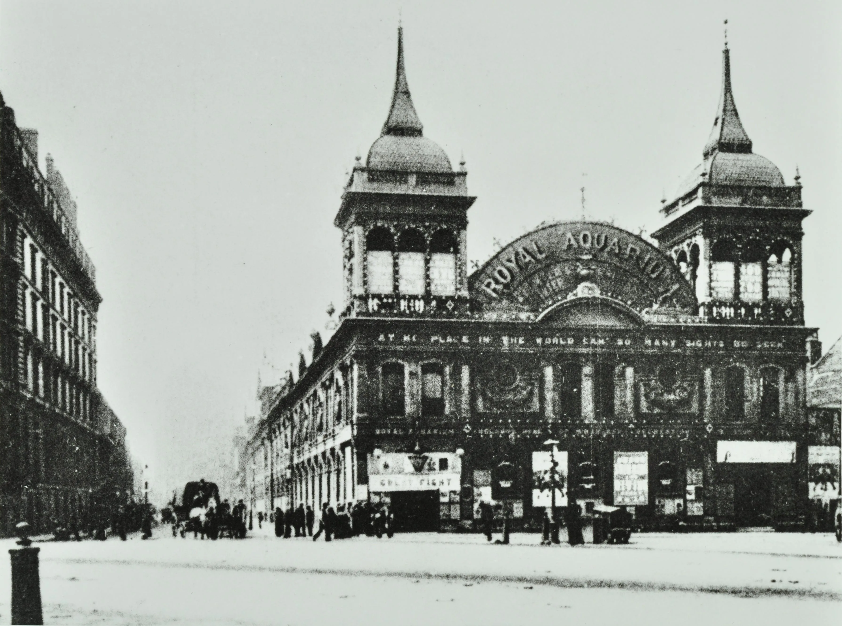 photograph of Royal Aquarium building with two pointed towers and people and horses in the vicinity