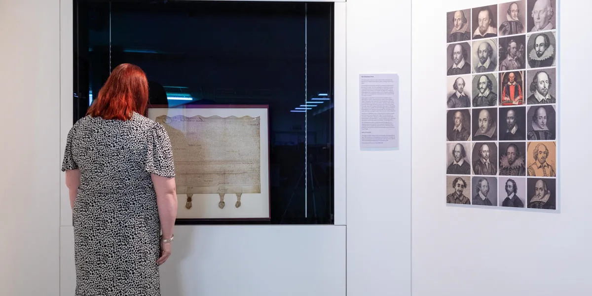 a visitor looks at a document with images of Shakespeare on the right hand side