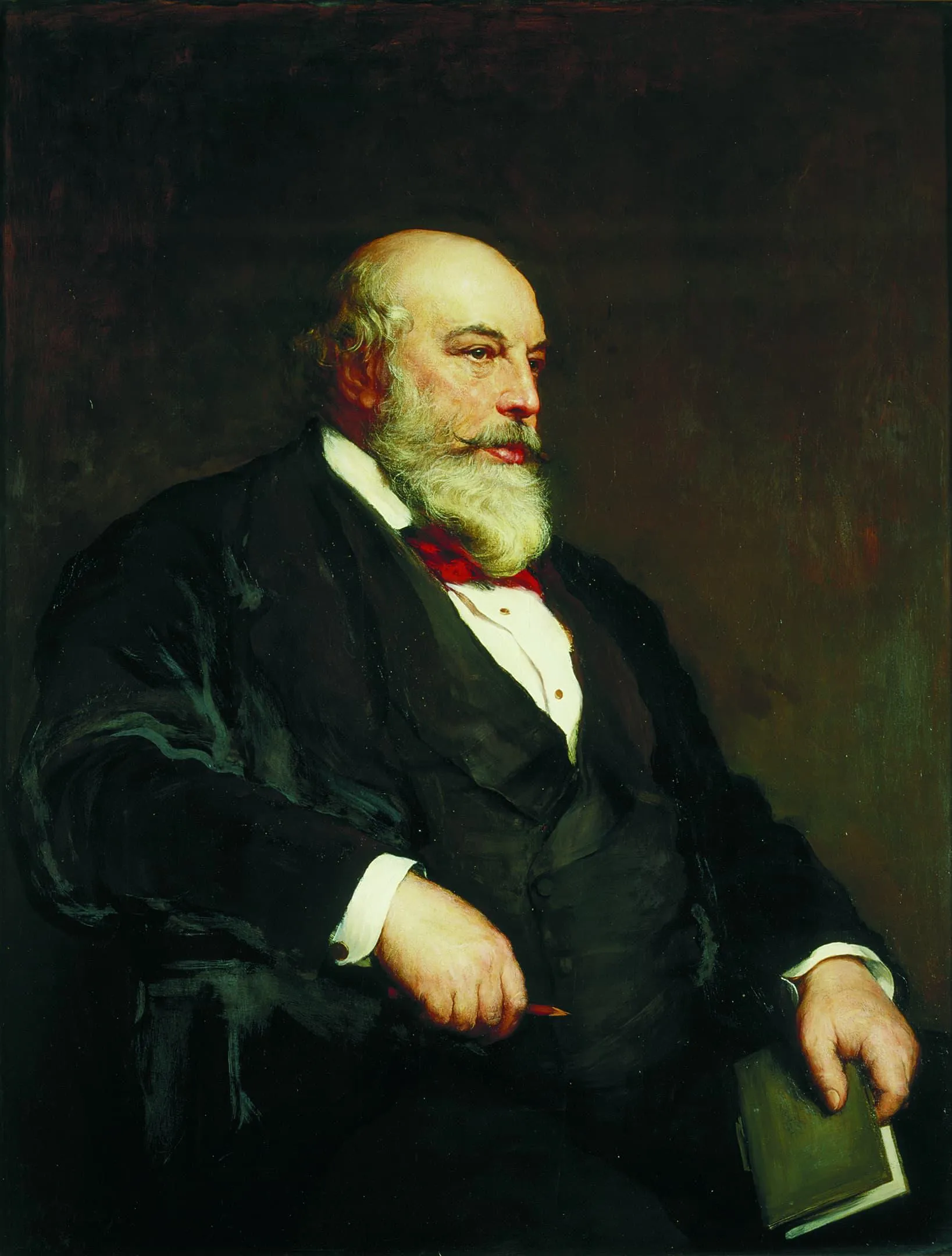 A man with a beard and black suit sitting down