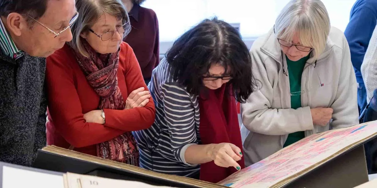 People looking at an archive volume and pointing at a detail
